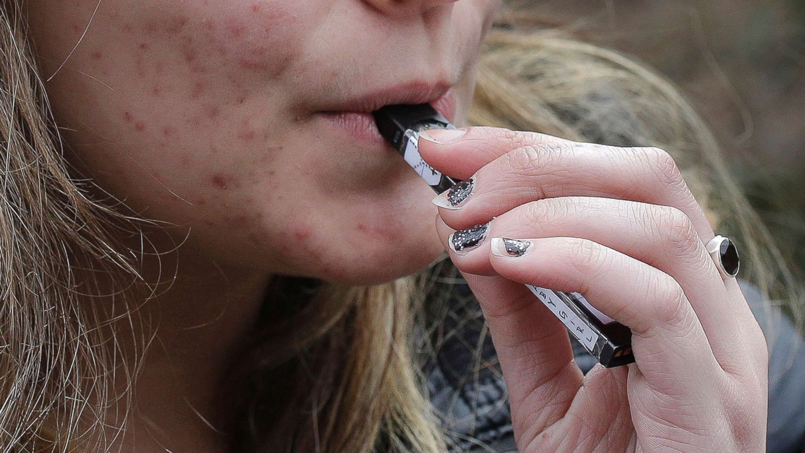 PHOTO: A high school student uses a vaping device near a school campus in Cambridge, Mass., April 11, 2018.