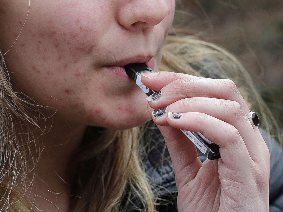 PHOTO: A high school student uses a vaping device near a school campus in Cambridge, Mass., April 11, 2018.