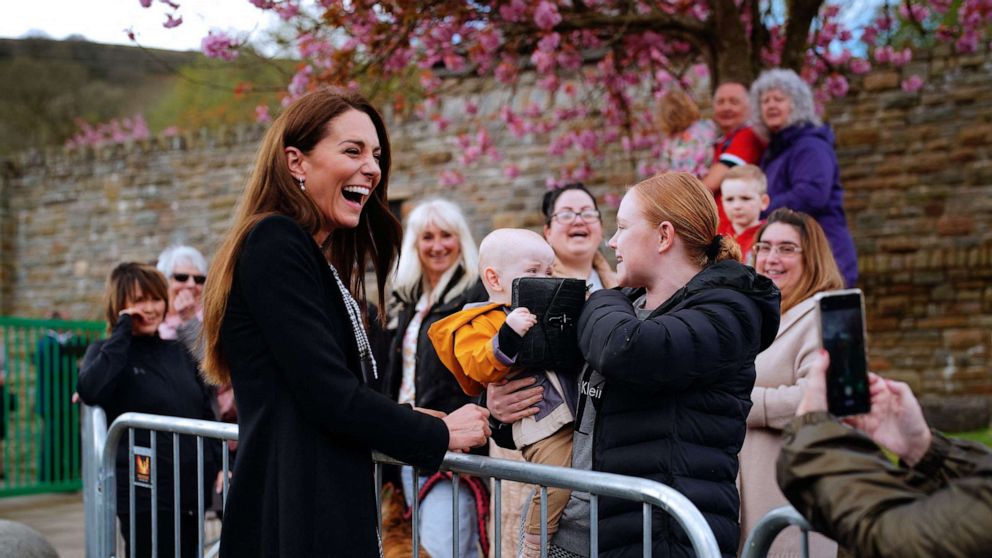 PHOTO: Lucy Williams from Aberfan, holds her son Daniel Williams as he takes the handbag of Britain's Catherine, Princess of Wales (L) during a visit with Britain's Prince William, Prince of Wales to the Aberfan memorial garden in Aberfan, south Wales on