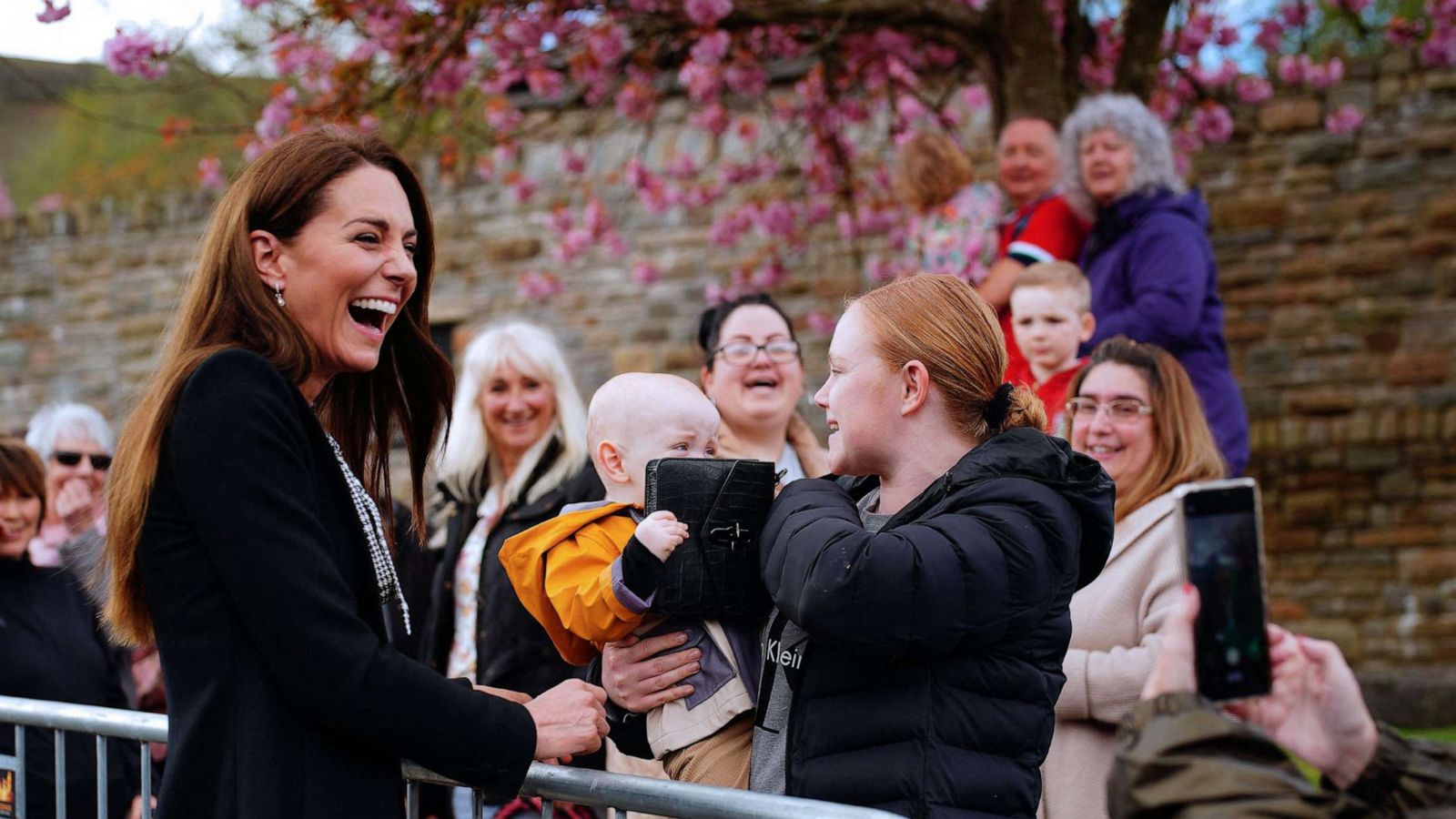 PHOTO: Lucy Williams from Aberfan, holds her son Daniel Williams as he takes the handbag of Britain's Catherine, Princess of Wales (L) during a visit with Britain's Prince William, Prince of Wales to the Aberfan memorial garden in Aberfan, south Wales on