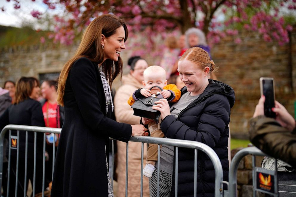 PHOTO: Lucy Williams, from Aberfan, holds her son Daniel Williams as he takes the handbag of Catherine, Princess of Wales, during her visit with her husband the Prince of Wales, to the Aberfan memorial garden in Aberfan, Wales, Britain, on April 28, 2023.