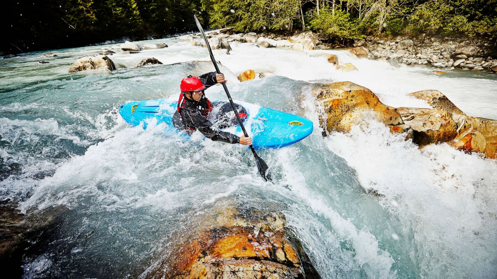 PHOTO: Kayaker entering white water rapids between narrow gap in rocks