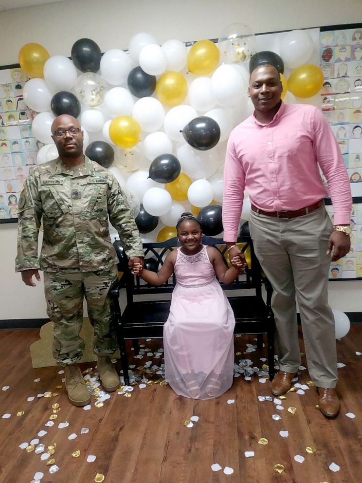 PHOTO: Kylar Matthews, 7, stands with her father, Kevin Matthews of the United States Army and her step-dad Kerlanders Watson, at Lamkin Elementary School's daddy-daughter dance in Texas, March 29, 2019.