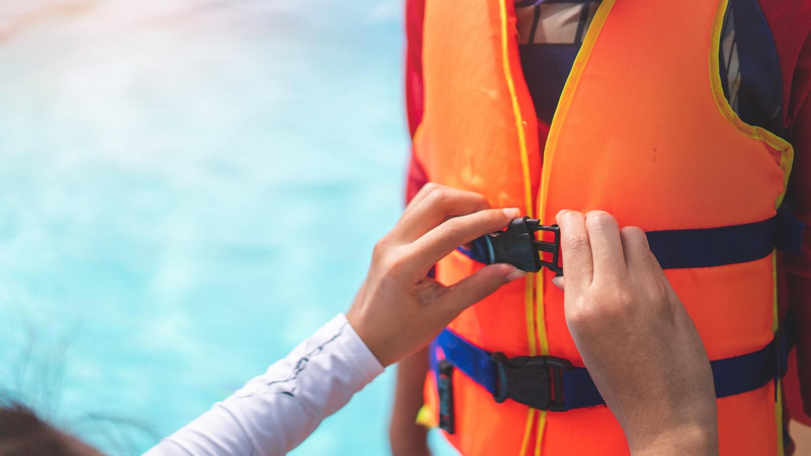 PHOTO: A mother helping her son to wear a life jacket before playing in swimming pool.