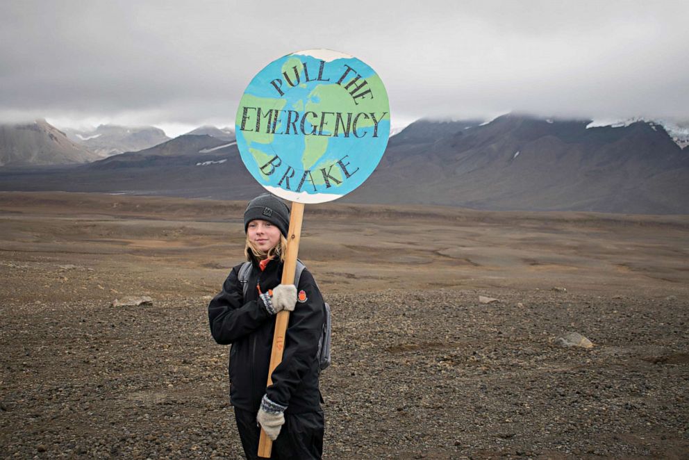PHOTO: An Icelandic girl poses for a photo with a "Pull the emergency brake" sign near to where a monument was unveiled at the site of Okjokull, Iceland's first glacier lost to climate change in the west of Iceland on Aug. 18, 2019.