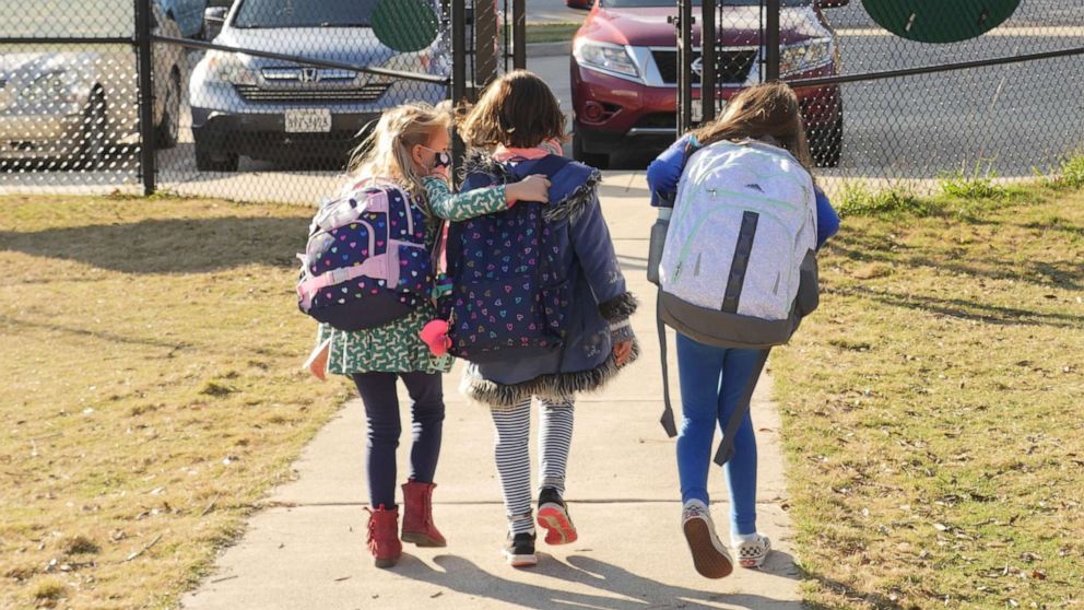 PHOTO: School children wearing facemasks walk outside an elementary school.