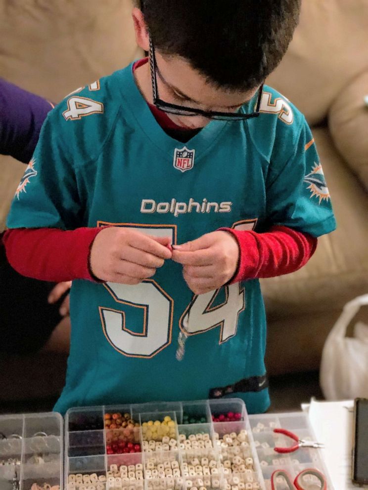 PHOTO: Keoni Ching, 8, makes kindness keychains for his school lunch debt project.