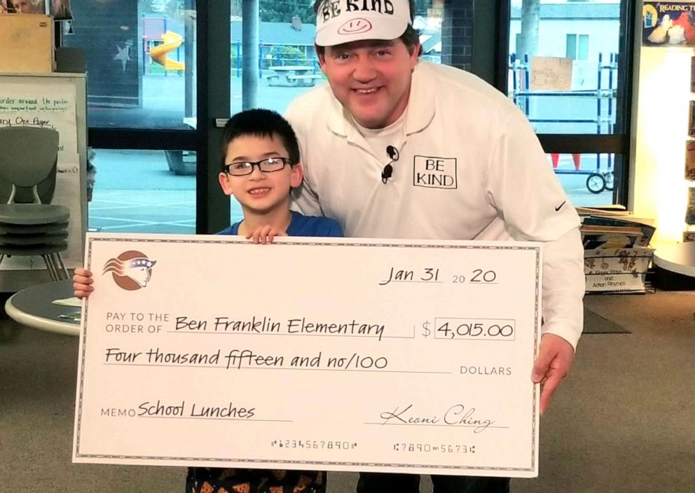 PHOTO: Keoni Ching presents a check to Benjamin Franklin Elementary School principal Woody Howard in Vancouver, Washington.