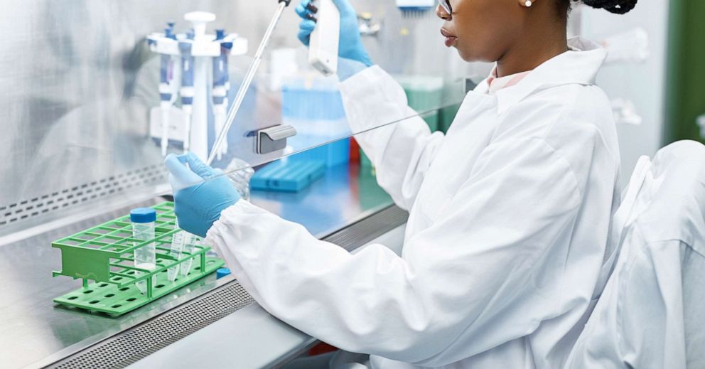 PHOTO: Female scientist analyzing medical sample in test tube. Young researcher is wearing lab coat. She is concentrating while working in laboratory.