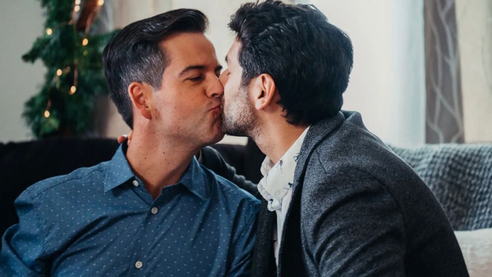 PHOTO: In this still from the 2019 Lifetime movie "Twinkle All The Way", actors Brian Sills and Mark Ghanime play a married couple.