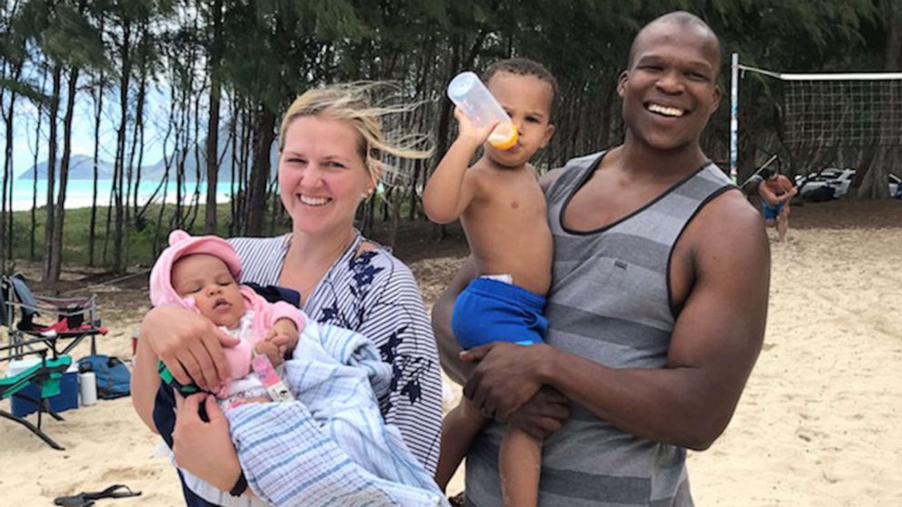 PHOTO: Lindani Myeni stands on the beach in Waimanalo, Hawaii, with his wife Lindsay and their two children in a family handout photo from 2021.