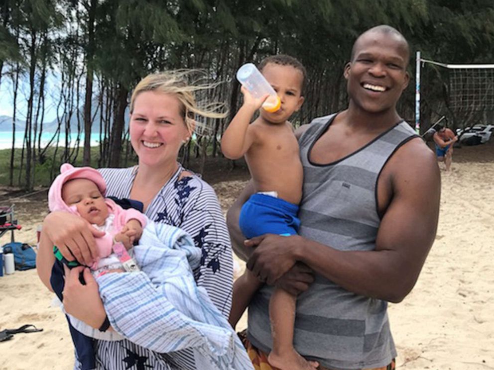 PHOTO: Lindani Myeni stands on the beach in Waimanalo, Hawaii, with his wife Lindsay and their two children in a family handout photo from 2021.