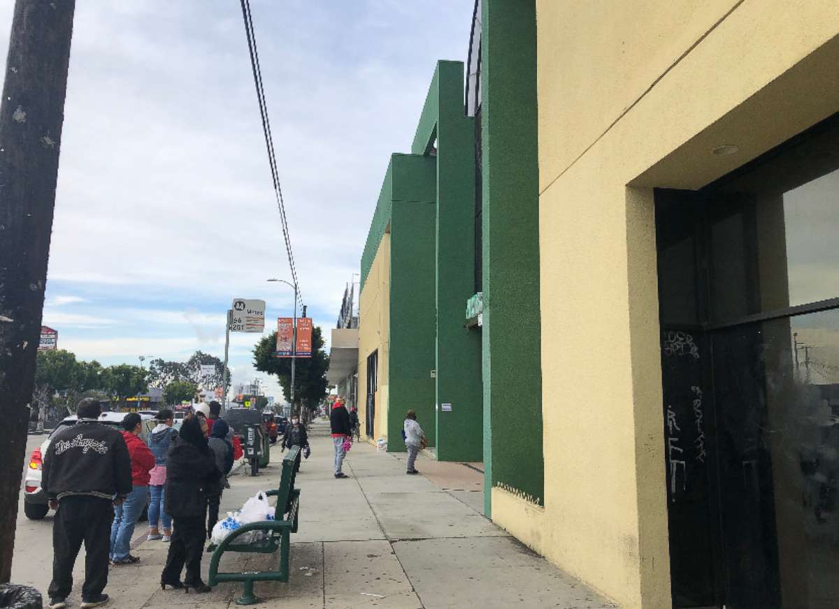 PHOTO: A line of parents and guardians wait to pick up free school lunches from Arts in Action Community Charter Schools in East Los Angeles during the pandemic.