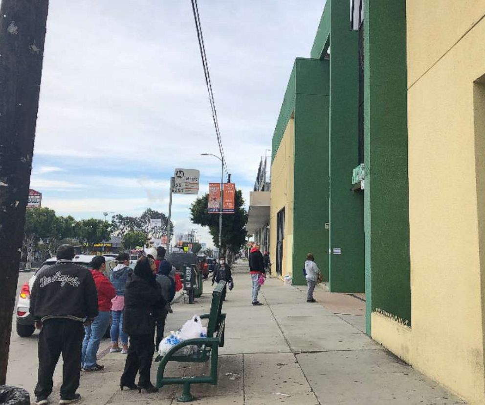 PHOTO: A line of parents and guardians wait to pick up free school lunches from Arts in Action Community Charter Schools in East Los Angeles during the pandemic.