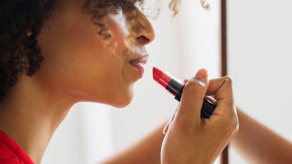 A woman applies lipstick in a mirror in an undated stock photo.