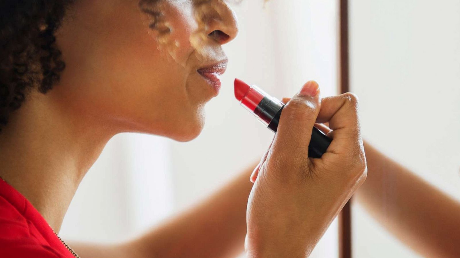 PHOTO: A woman applies lipstick in a mirror in an undated stock photo.