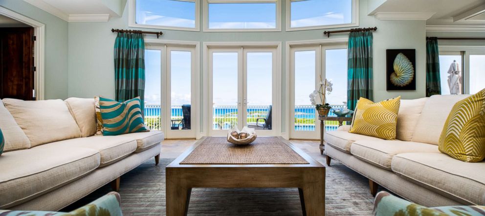 PHOTO: A living room with floor to ceiling windows overlooking the bright aquamarine waters of Emerald Bay. 