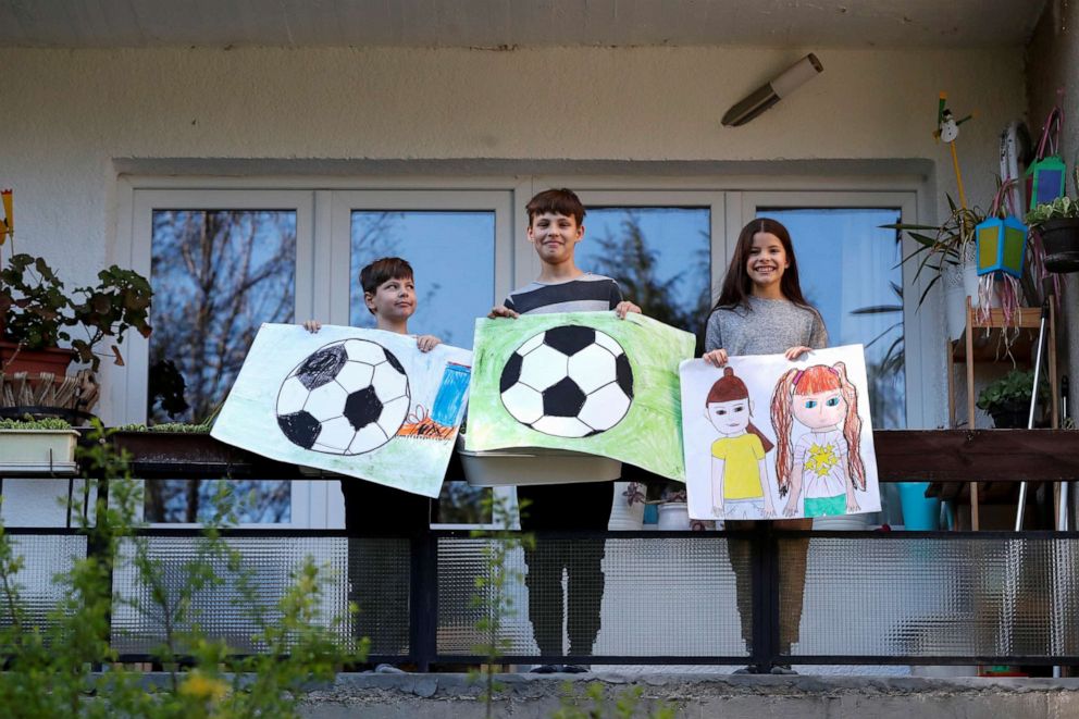PHOTO: Ivan Posta, 8, Vince Posta, 11, and Vilma Posta, pose for a photograph while holding pictures that they drew during the Coronavirus disease (COVID-19) outbreak, while standing on the balcony at their home in Budapest, Hungary, April 10, 2020.