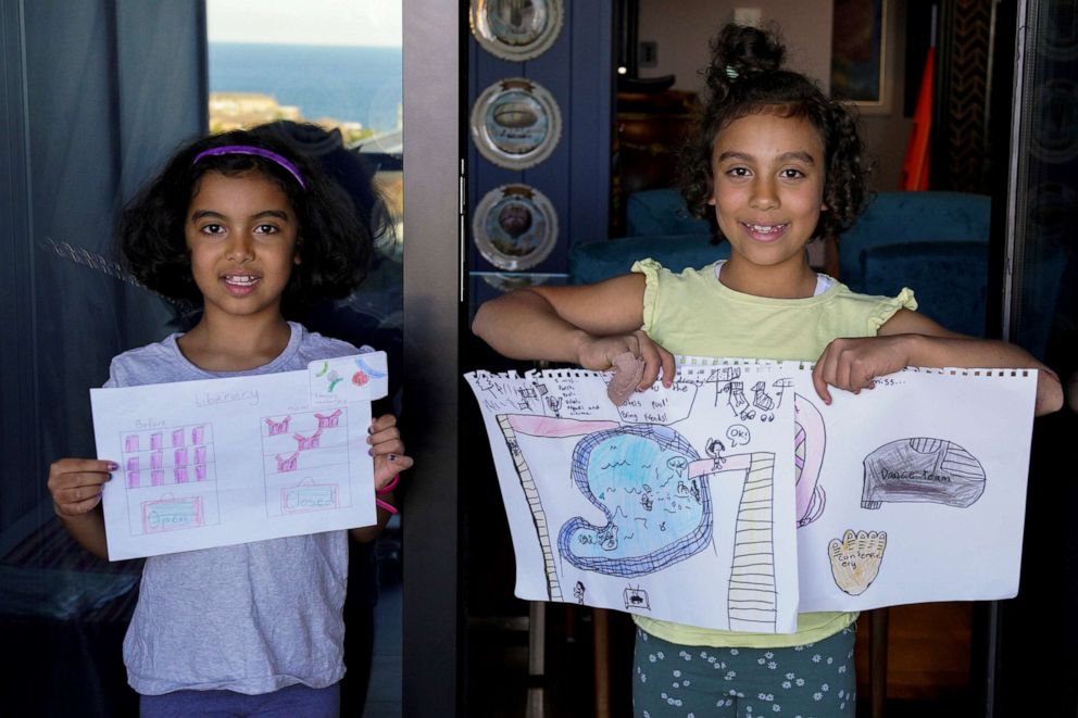 PHOTO: Oriana Ikladious and Rafaela Ikladious, 8, who are twins, pose while holding pictures that they drew during the coronavirus outbreak, as they stand on the balcony at their home in Sydney, April 18, 2020.
