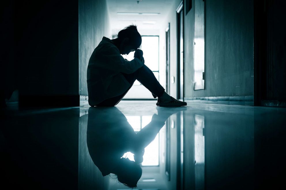 PHOTO: In this undated stock photo, the silhoutte of a young woman is shown sitting alone in a hallway.