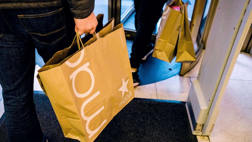 People carrying shopping bags exit Macy's flagship store in Herald Square in New York City, Nov. 27, 2020.