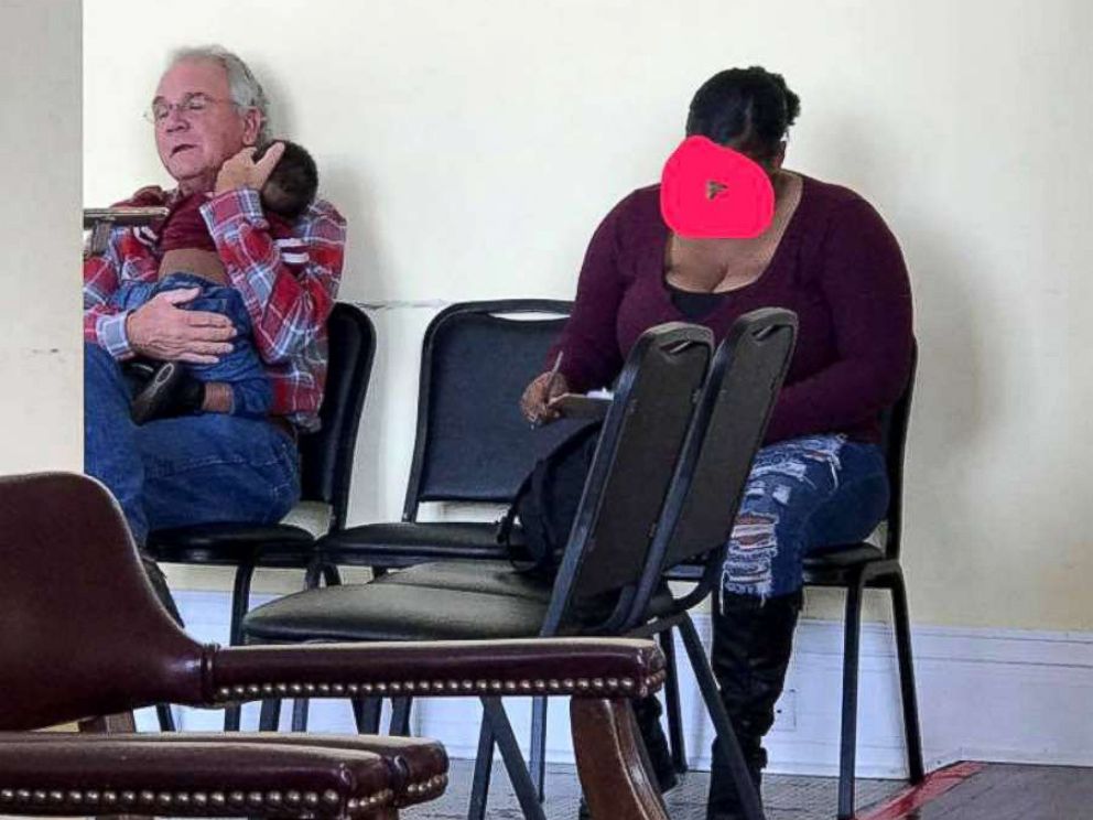 PHOTO: A photo of a man holding a sleeping baby while the mother fills out forms has gone viral.