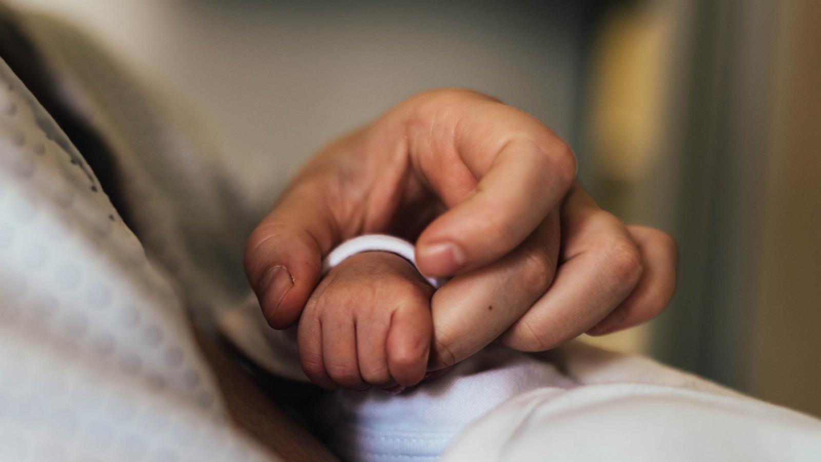 PHOTO: Mother's hand holding her newborn baby's hand in the hospital.