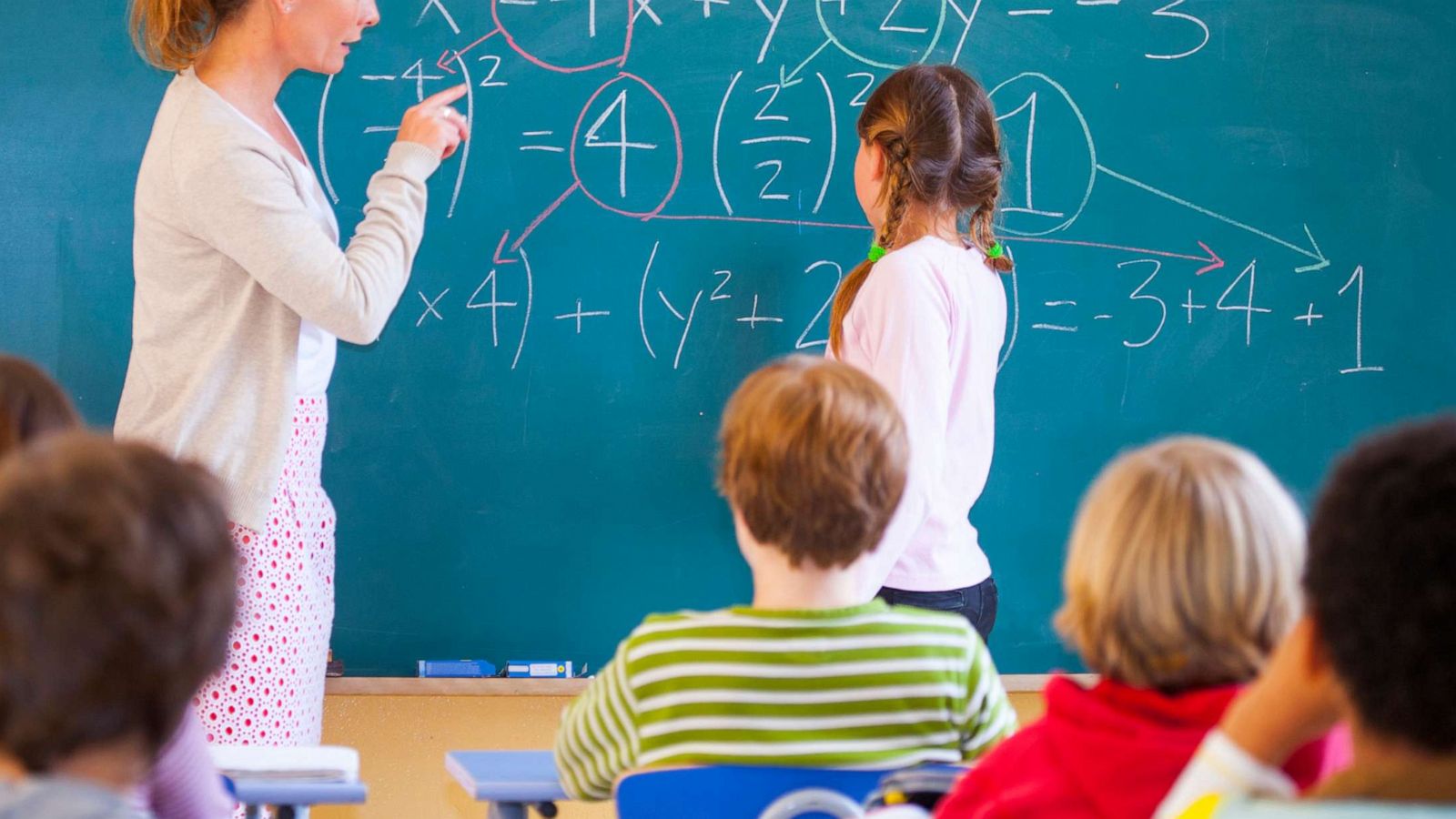 PHOTO: A teacher helps a student with a math problem in a classroom.