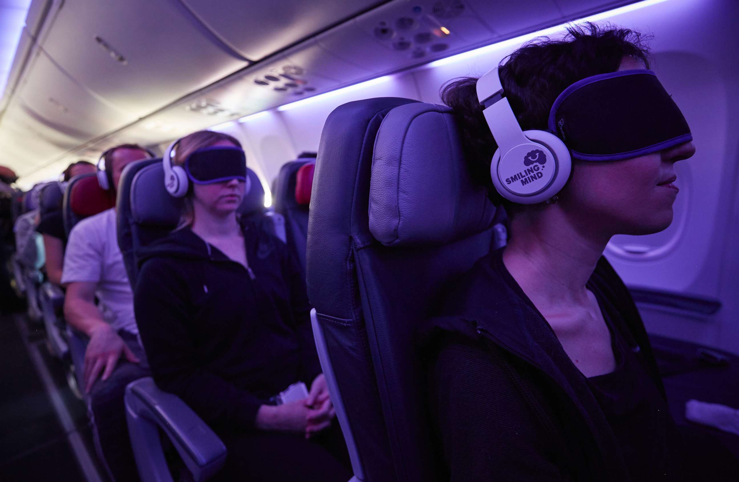 PHOTO: Passengers use headphones and eye masks to relax while on an airplane. 