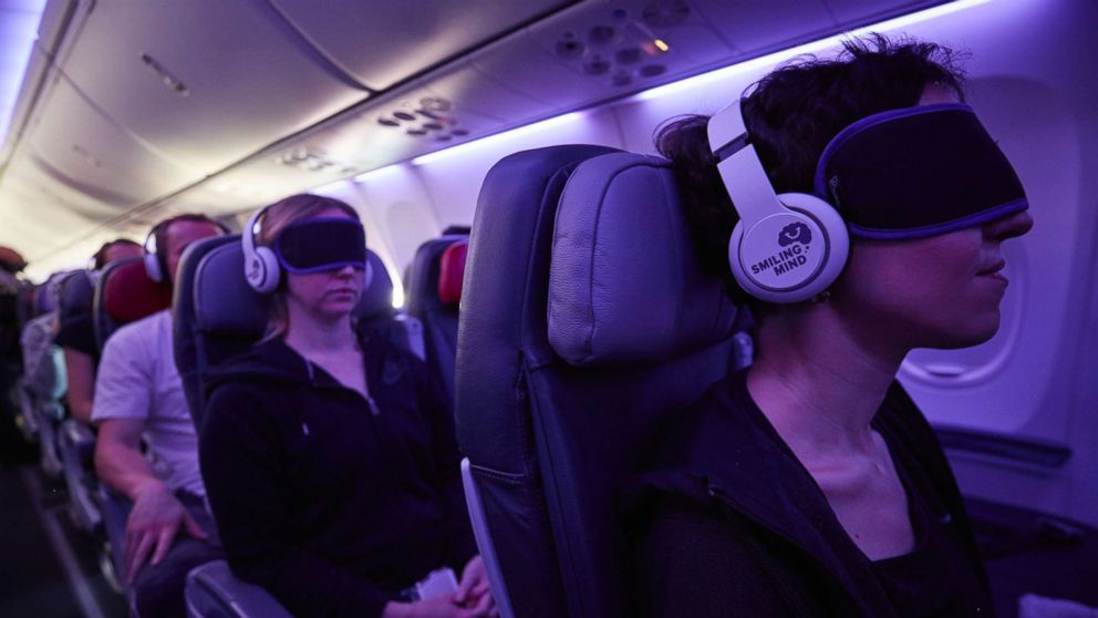 PHOTO: Passengers use headphones and eye masks to relax while on an airplane. 