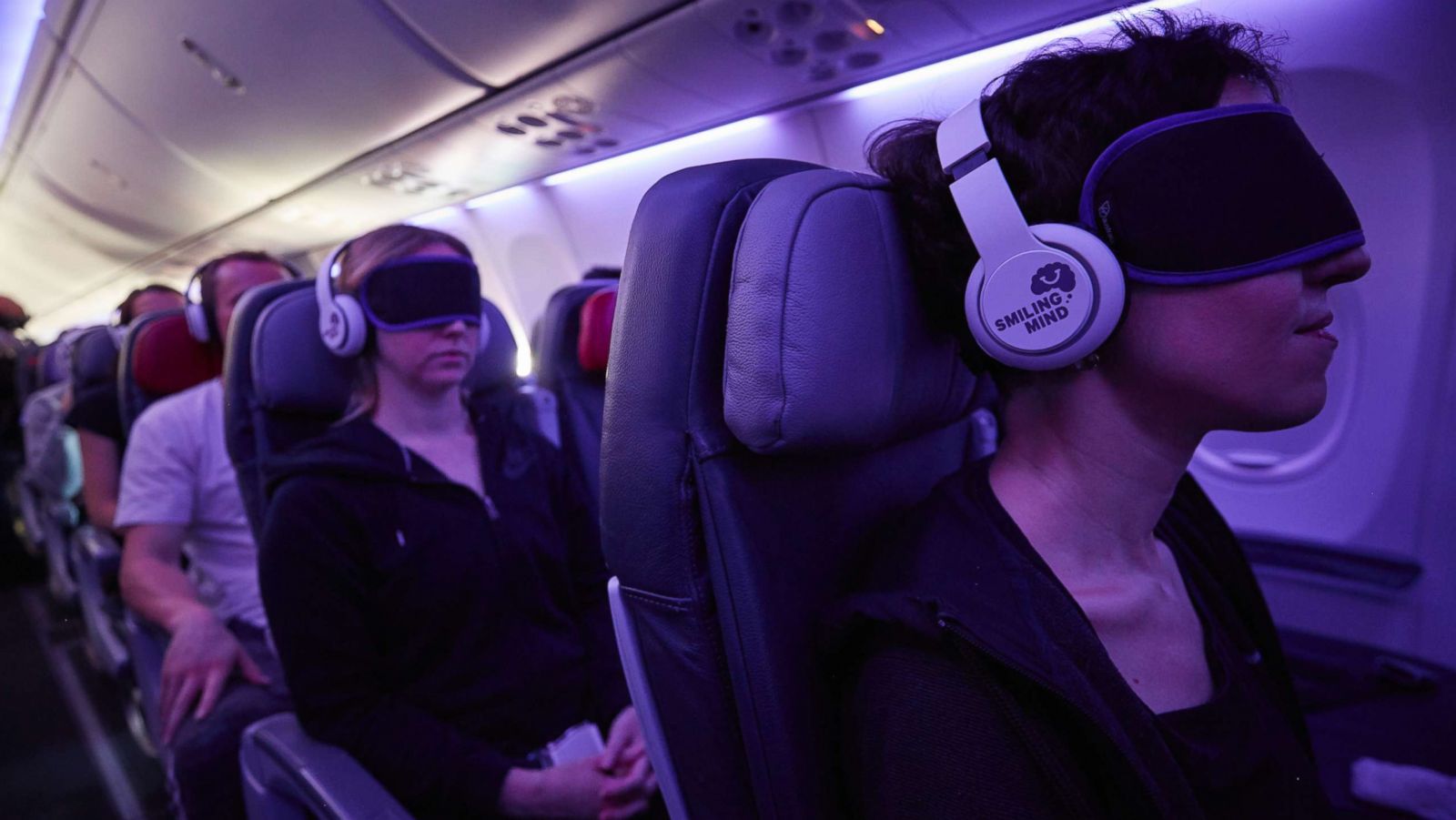 PHOTO: Passengers use headphones and eye masks to relax while on an airplane.