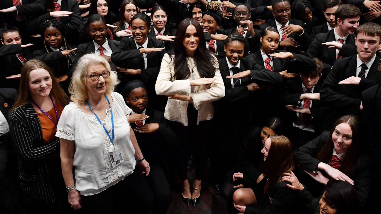 PHOTO: Meghan, Duchess of Sussex poses with school children making the 'Equality' sign following a school assembly during a visit to Robert Clack School in Dagenham to attend a special assembly ahead of International Women's Day, March 6, 2020 in London.