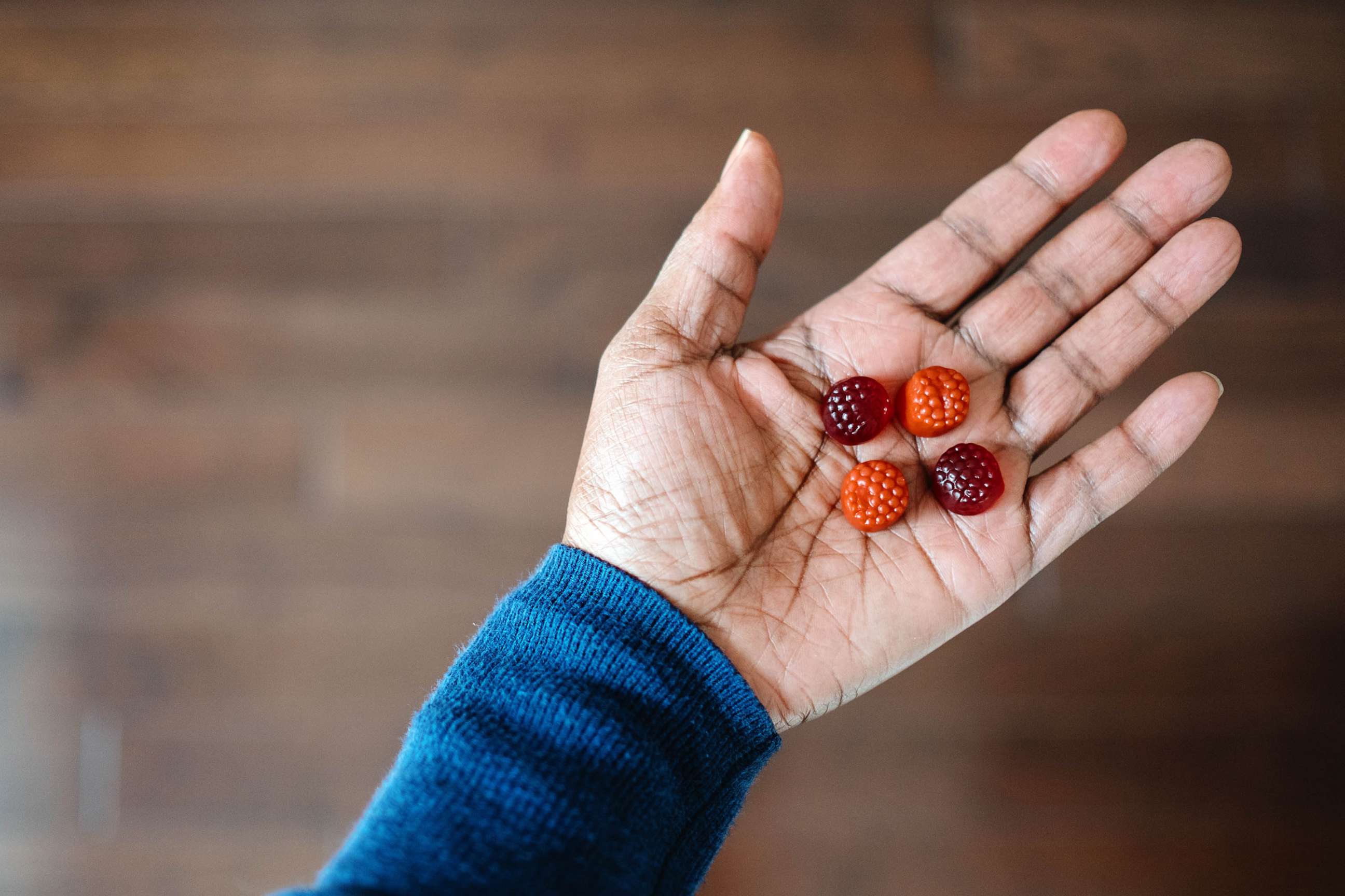 STOCK PHOTO: A woman hold four gummy supplements in the palm of her hand