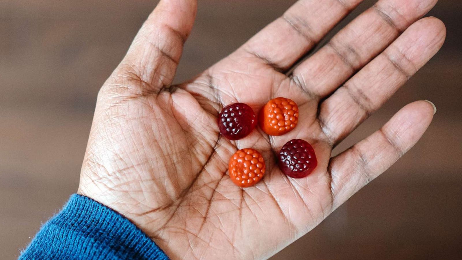 STOCK PHOTO: A woman hold four gummy supplements in the palm of her hand