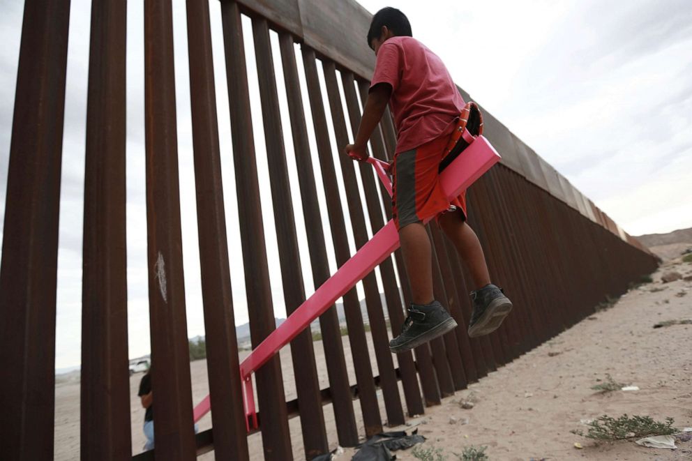 PHOTO: A child plays on a seesaw installed between the border fence that divides Mexico from the United States in Ciudad de Juarez, Mexico, July 28, 2019. The seesaw was designed by Ronald Rael, a professor of architecture in California.