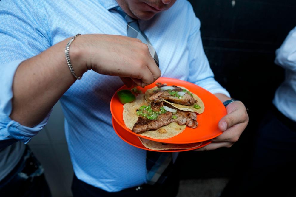 PHOTO: A customer finishes squeezing lime juice on his tacos at the Tacos El Califa de León stand, in Mexico City, May 15, 2024. 