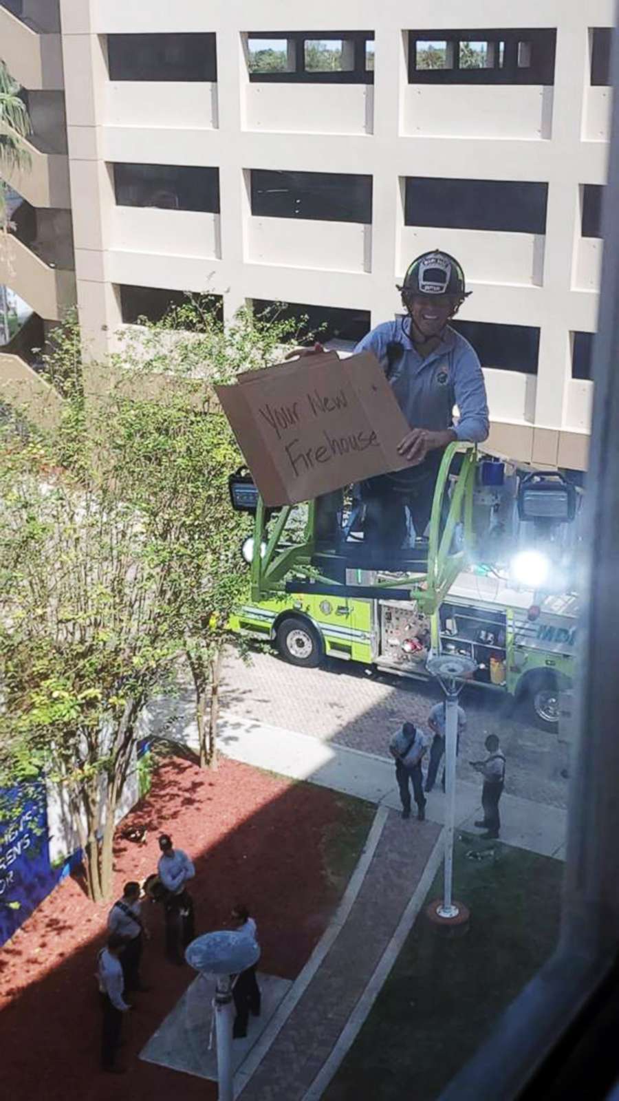 PHOTO: A firefighter holds a sign that says, "Your new firehouse," while visiting a fellow lieutenant hospitalized in Miami-Dade County, Fla., April 3, 2020.