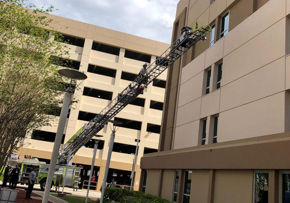 PHOTO: Firefighters climb the ladder from the fire truck to visit with their colleague through the fourth floor window of a hospital in Miami-Dade County, Fla., April 3, 2020.