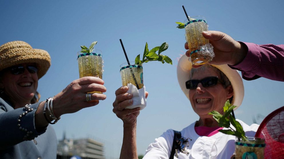 Racegoers who traveled to Churchill Downs from Colorado toast their mint julep bourbon cocktails while watching horse races on the eve of the Kentucky Derby in Louisville, Ky., May 1, 2015.