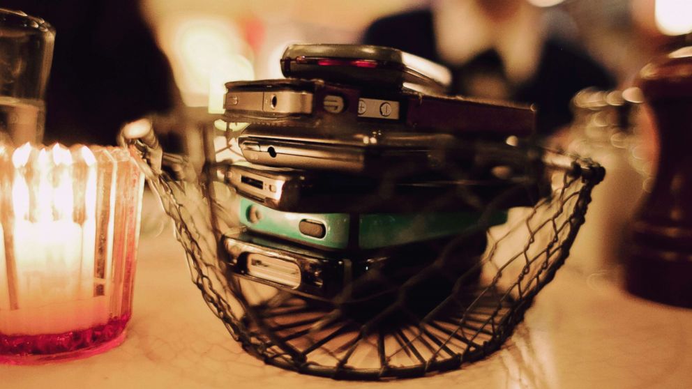 Cell phones in a basket on a table.