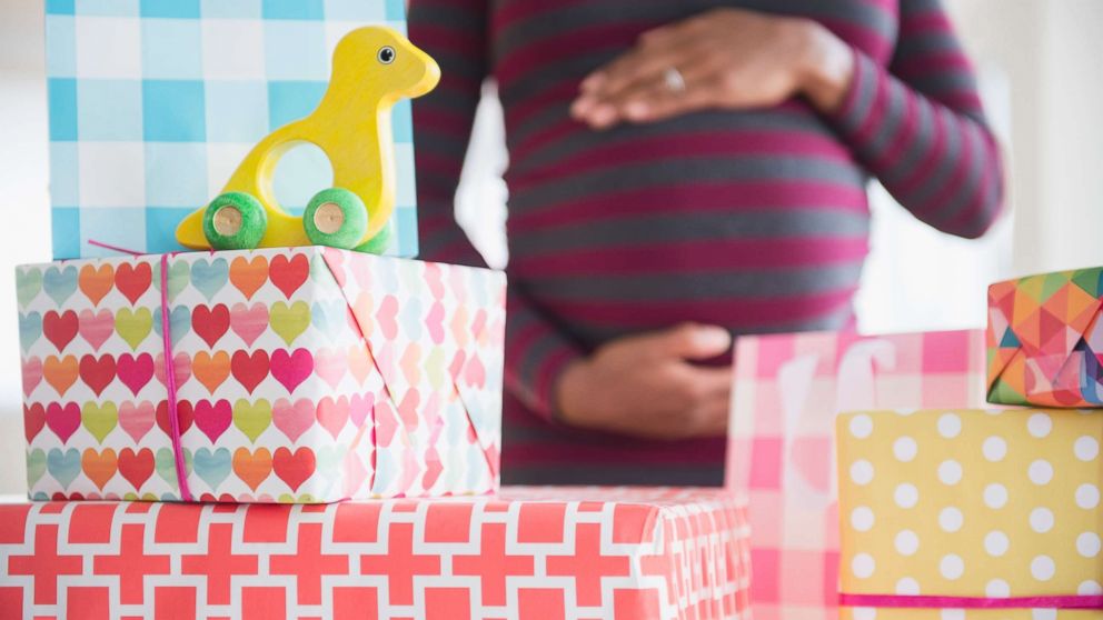 A pregnant woman is surrounded by gifts in an undated stock photo.