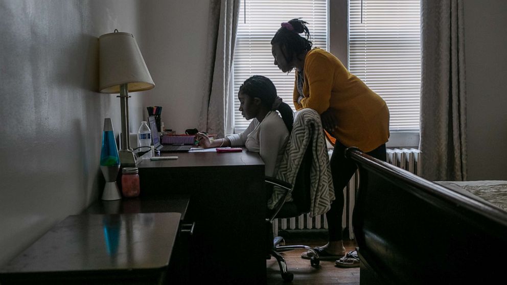 PHOTO: Abigail Previlon, 13, takes part in remote distance learning on a Chromebook with the help of her mother Carlene at home on Oct. 28, 2020, in Stamford, Conn.