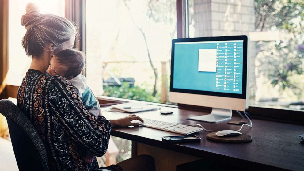 PHOTO: In this undated file image, a woman works from home while holding her newborn son.