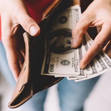 PHOTO: Stock photo of a person taking cash out of a wallet.