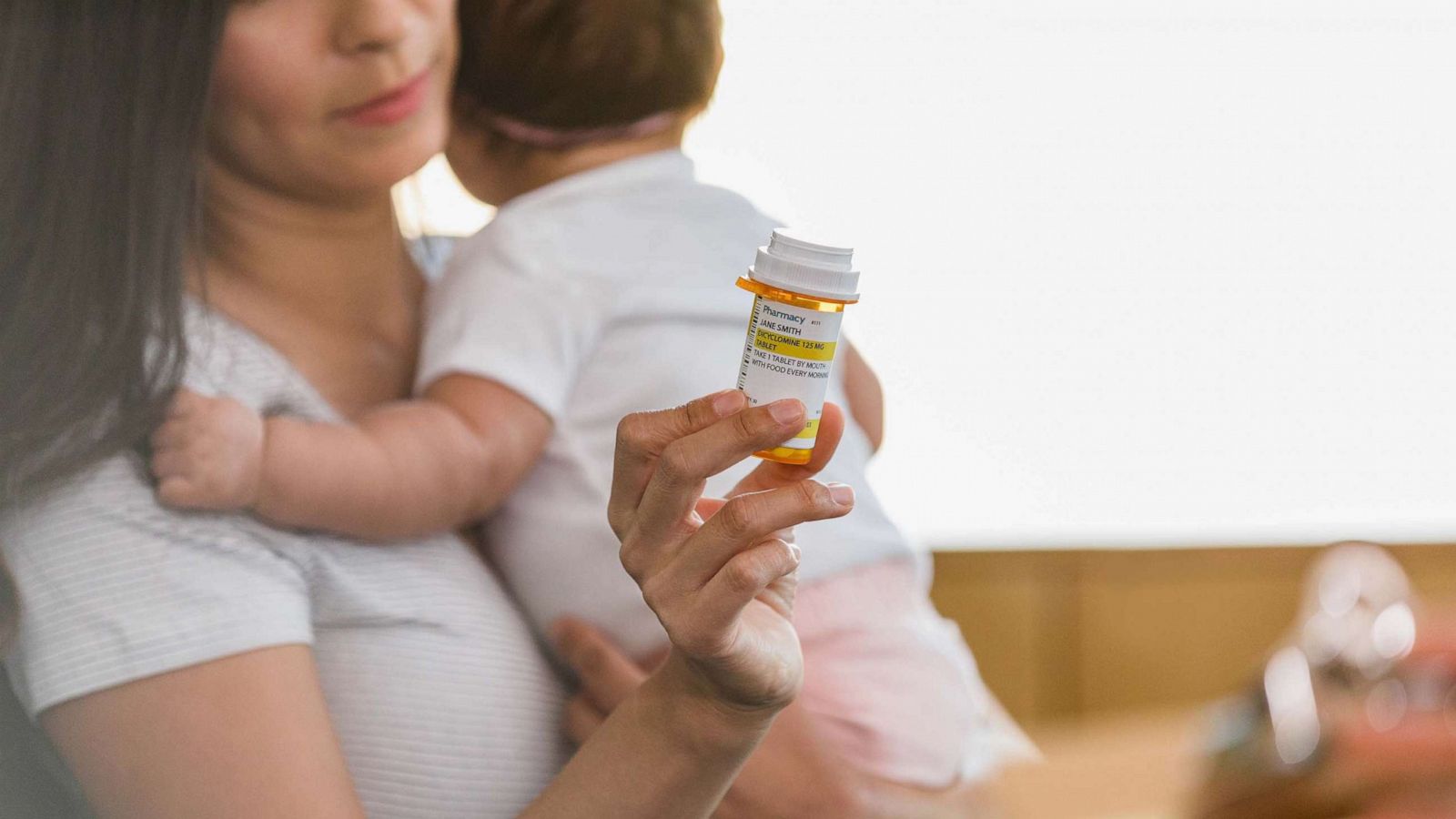 PHOTO: A depressed new mom cradles her baby as she holds out the prescription pill bottle to show to the unseen mental health professional.