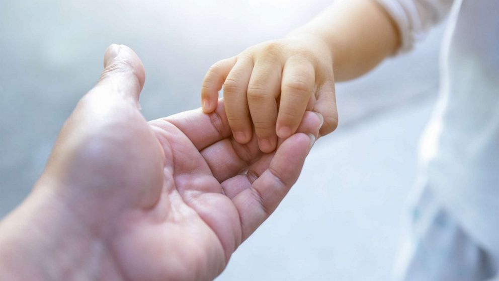 PHOTO: A woman holds a young child's hand.