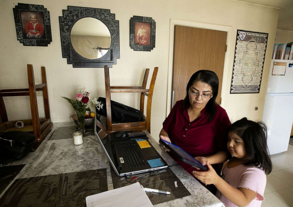 PHOTO: Farrah Begay helps her daughter, Namaiyah Yazzie, 4, with her tablet while Begay works from home on her laptop as an office assistant and registrar in Chilchinbeto on the Navajo Nation in Ariz., Feb. 16, 2021. 