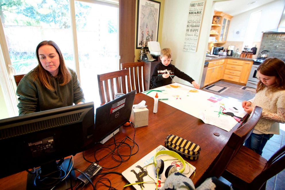 PHOTO: Kim Borton works from home while her children Logan and Katie Borton work on an art project in Beaverton, Ore., March 17, 2020.