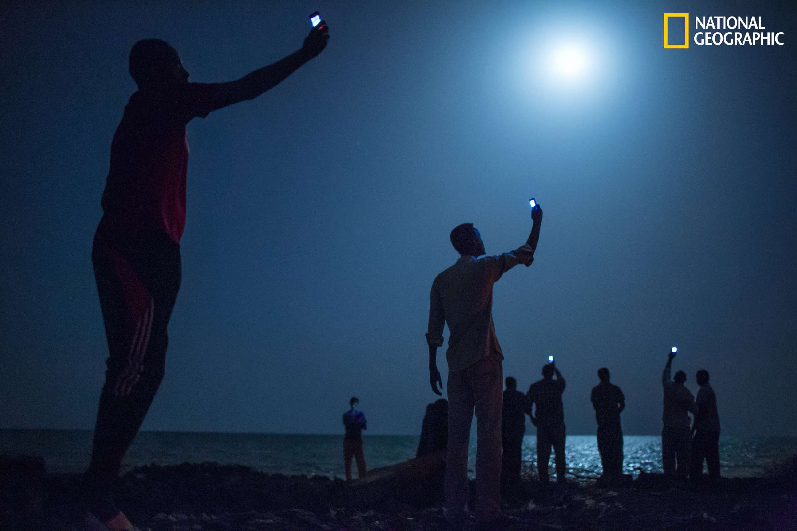 PHOTO: Impoverished African migrants crowd the night shore of Djibouti city, trying to capture inexpensive cell signals from neighboring Somalia—a tenuous link to relatives abroad.