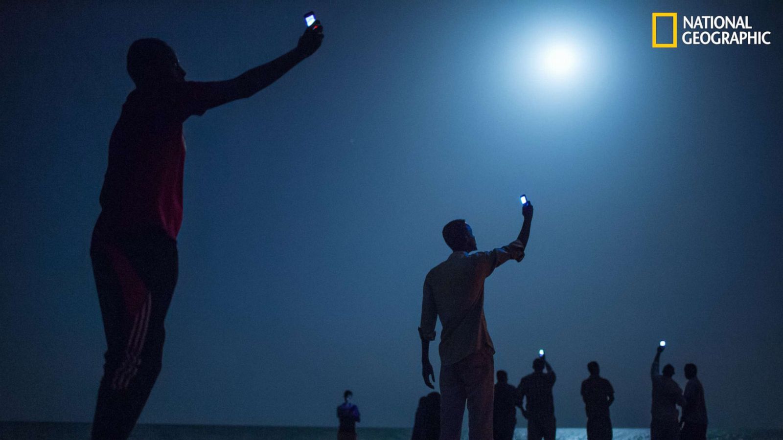 PHOTO: Impoverished African migrants crowd the night shore of Djibouti city, trying to capture inexpensive cell signals from neighboring Somalia—a tenuous link to relatives abroad.